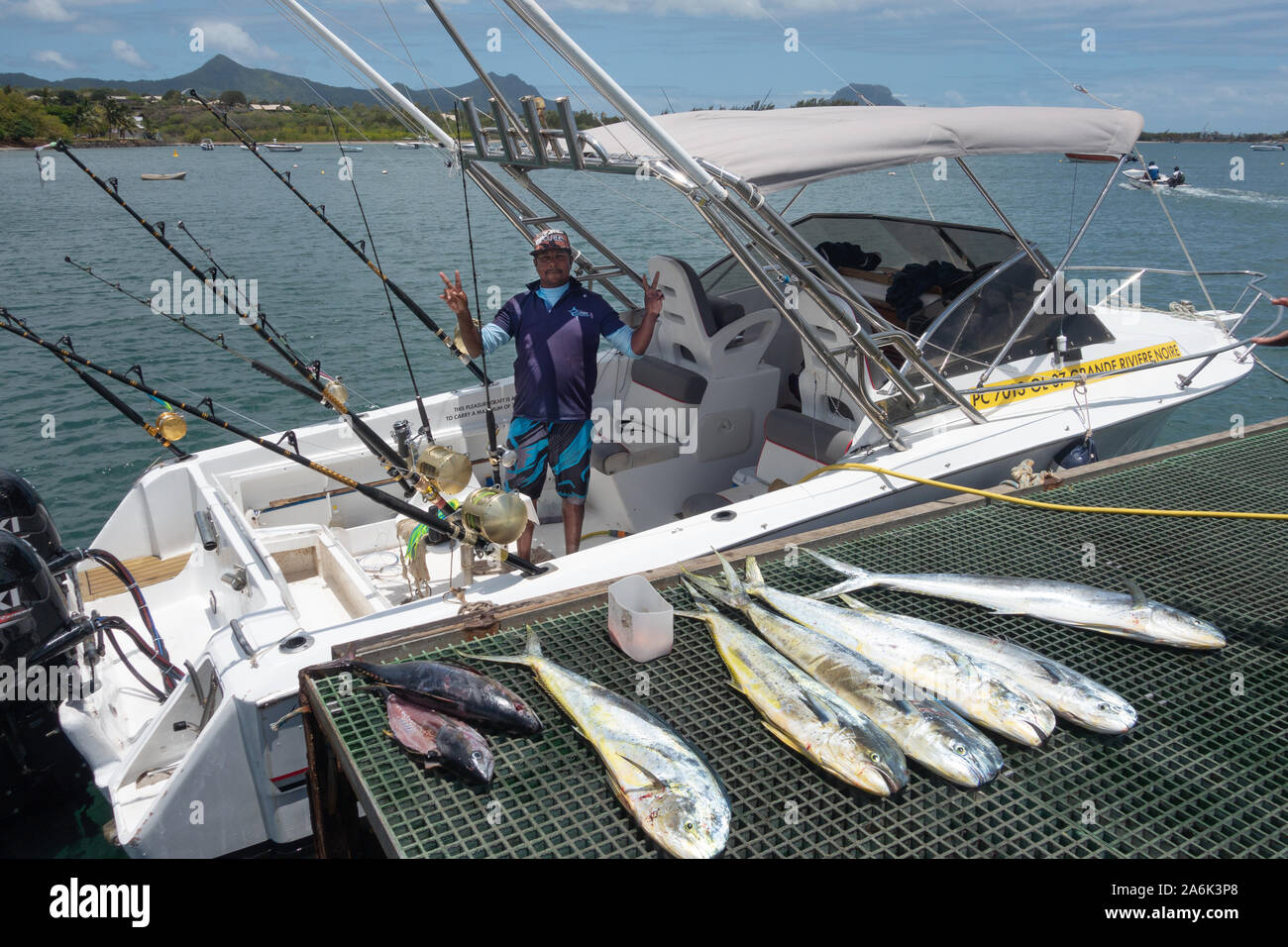 Pêche à Maurice ; un pêcheur mauricien posant avec son bateau et de montrer ses prises de poissons ; Le Morne, Île Maurice Banque D'Images