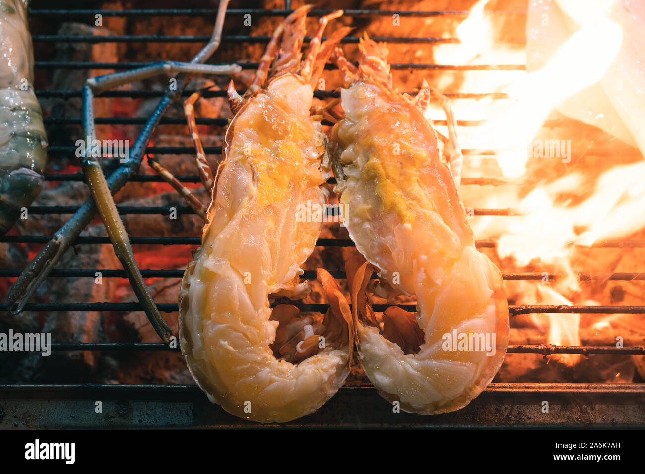 Close up of flame Homard grillé, coupé en deux et griller sur un barbecue en plein air à un décrochage du marché de l'alimentation de rue - des fruits de mer plage dîner buffet, y compris les crevettes géantes et les poissons cuits sur grill ouvert Banque D'Images