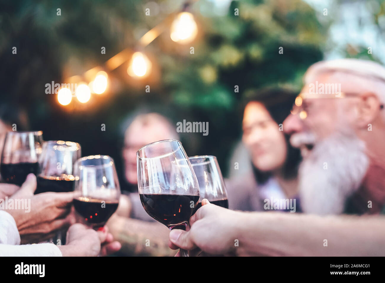 Famille heureuse de manger et de boire du vin rouge au dîner barbecue en plein air - jeunes et matures de clameurs et de verre sur le toit Banque D'Images