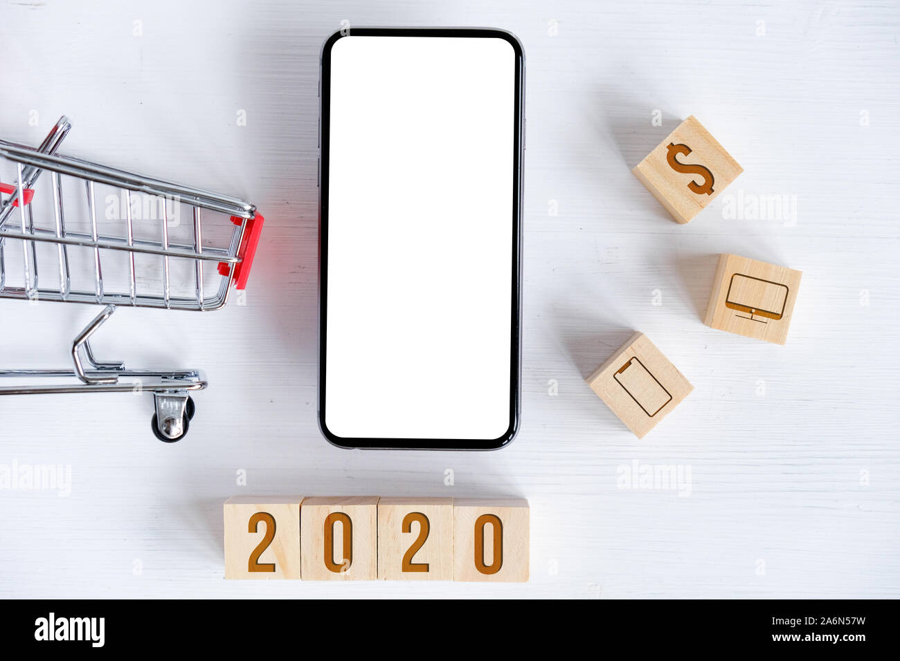 Des maquettes de smartphone avec toy panier, cubes avec symboles peints de 2020, monobloc, dollar. Concept de vente en ligne, des cadeaux de Noël. Banque D'Images
