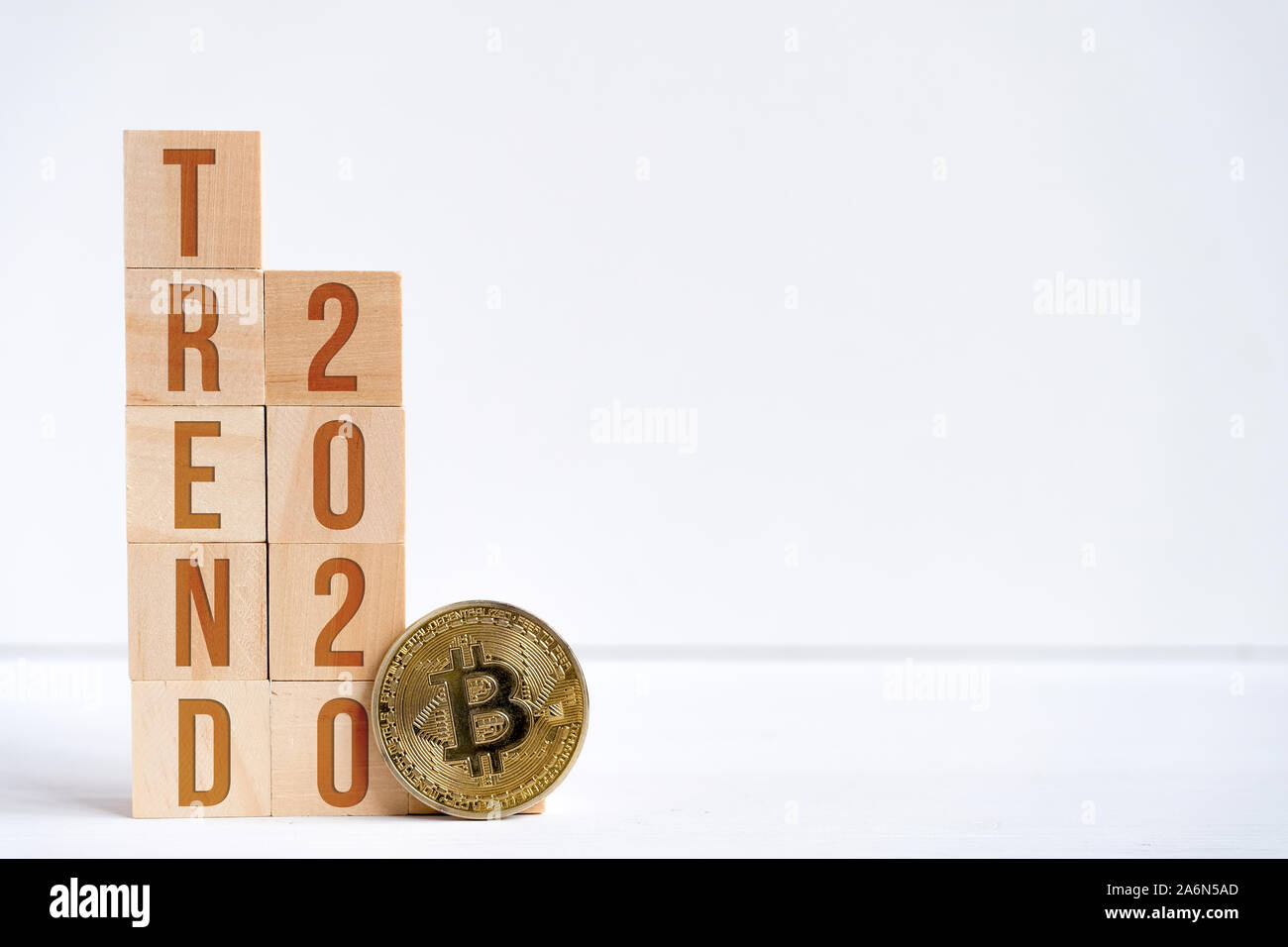 Chiffres 2020 et mot tendance sur les cubes en bois à côté de bitcoin. Le concept de la demande élevée et le succès d'cryptocurrency dans la nouvelle année. Copier l'espace. Banque D'Images