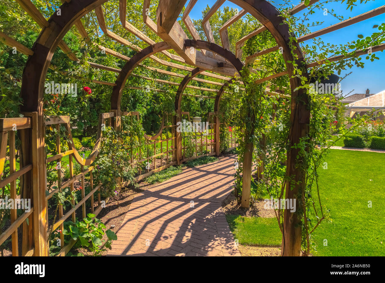 Arbor en bois dans une salle de mariage avec plantes vertes luxuriantes et brique pierre pathway Banque D'Images