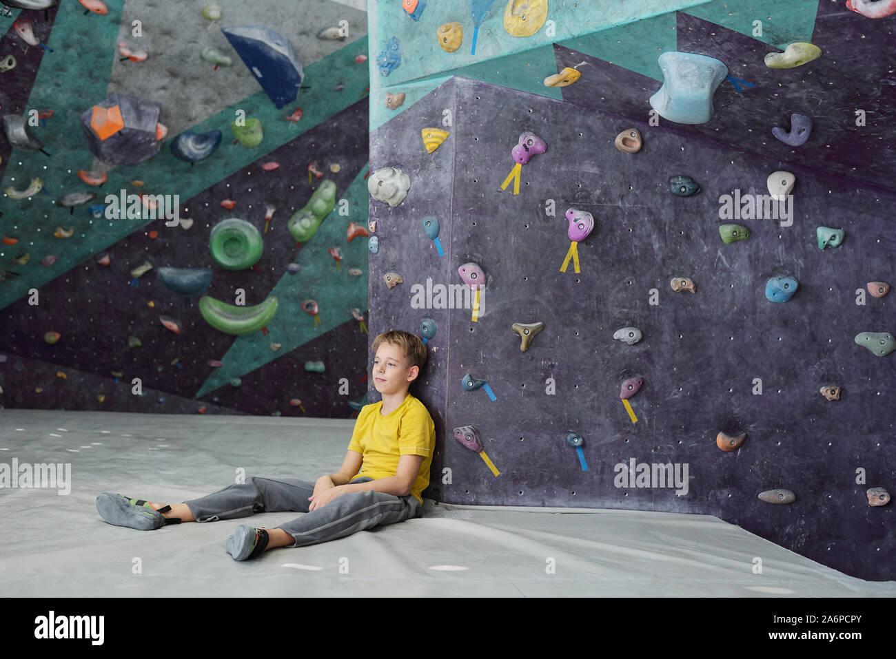 Écolier reposant dans activewear assis contre le mur d'escalade après la formation Banque D'Images