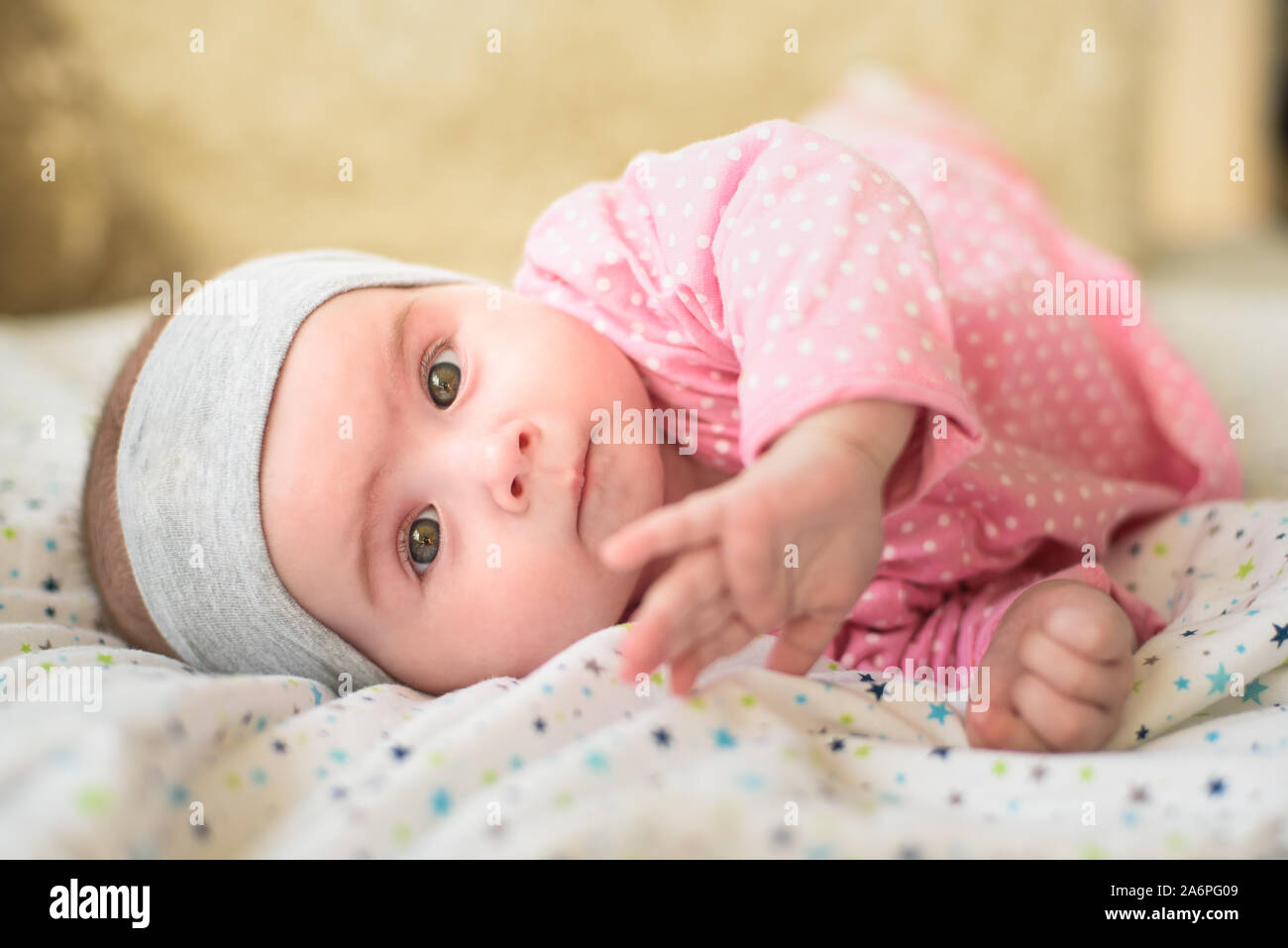 Jolie Petite Fille De 6 Mois Sur Un Lit Bebe Sur Son Ventre Avec La Tete Jusqu A La Recherche En Appareil Photo Avec Ses Gros Yeux La Lumiere Naturelle Photo Stock
