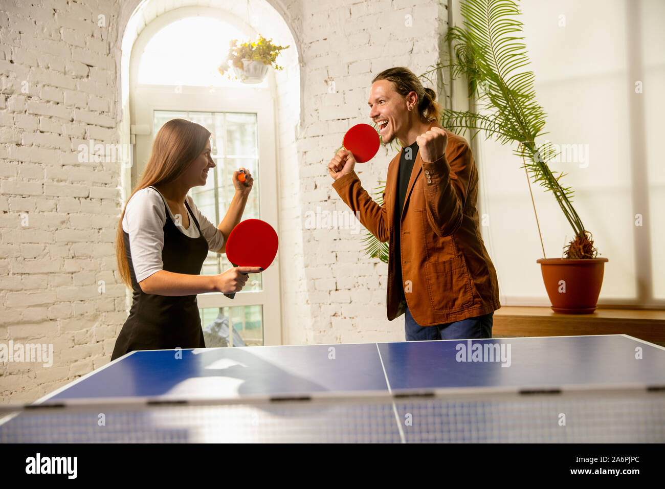 Les jeunes à jouer au tennis de table en milieu de travail, d'avoir du  plaisir. Les amis dans les tenues de jouer ensemble au ping-pong journée  ensoleillée. Concept de l'activité de loisirs,
