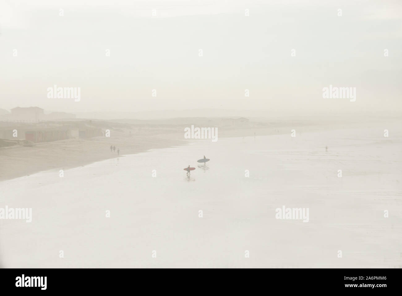 Surfers dans le brouillard au petit matin à une longue étendue de Muizenberg Beach sur la False Bay, Cape Town Afrique du Sud Banque D'Images