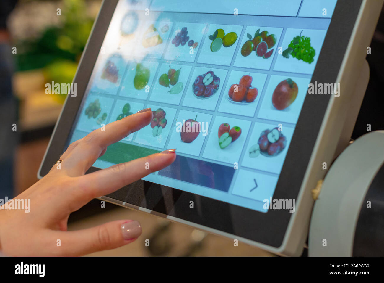 Une femme est à la recherche d'un produit fruits affectés à l'écran de balances électroniques pour le pesage Banque D'Images