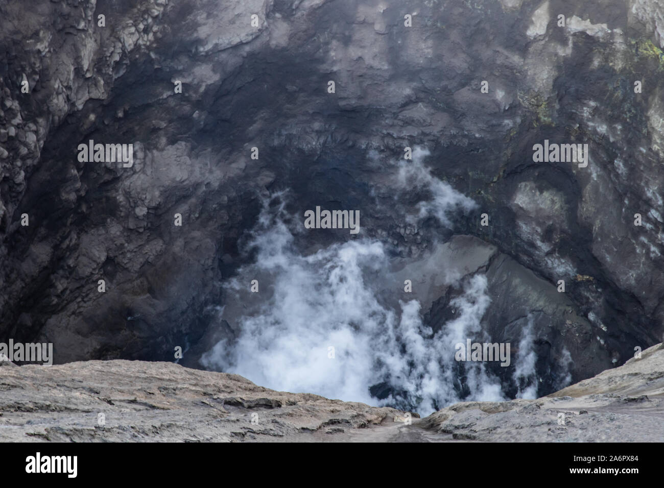 Gros plan de l'intérieur du cratère du Mont Bromo, Java Est, Indonésie. Gaz volcanique blanche passant de ci-dessous ; le soufre jaune incrusté dans la roche en face Banque D'Images