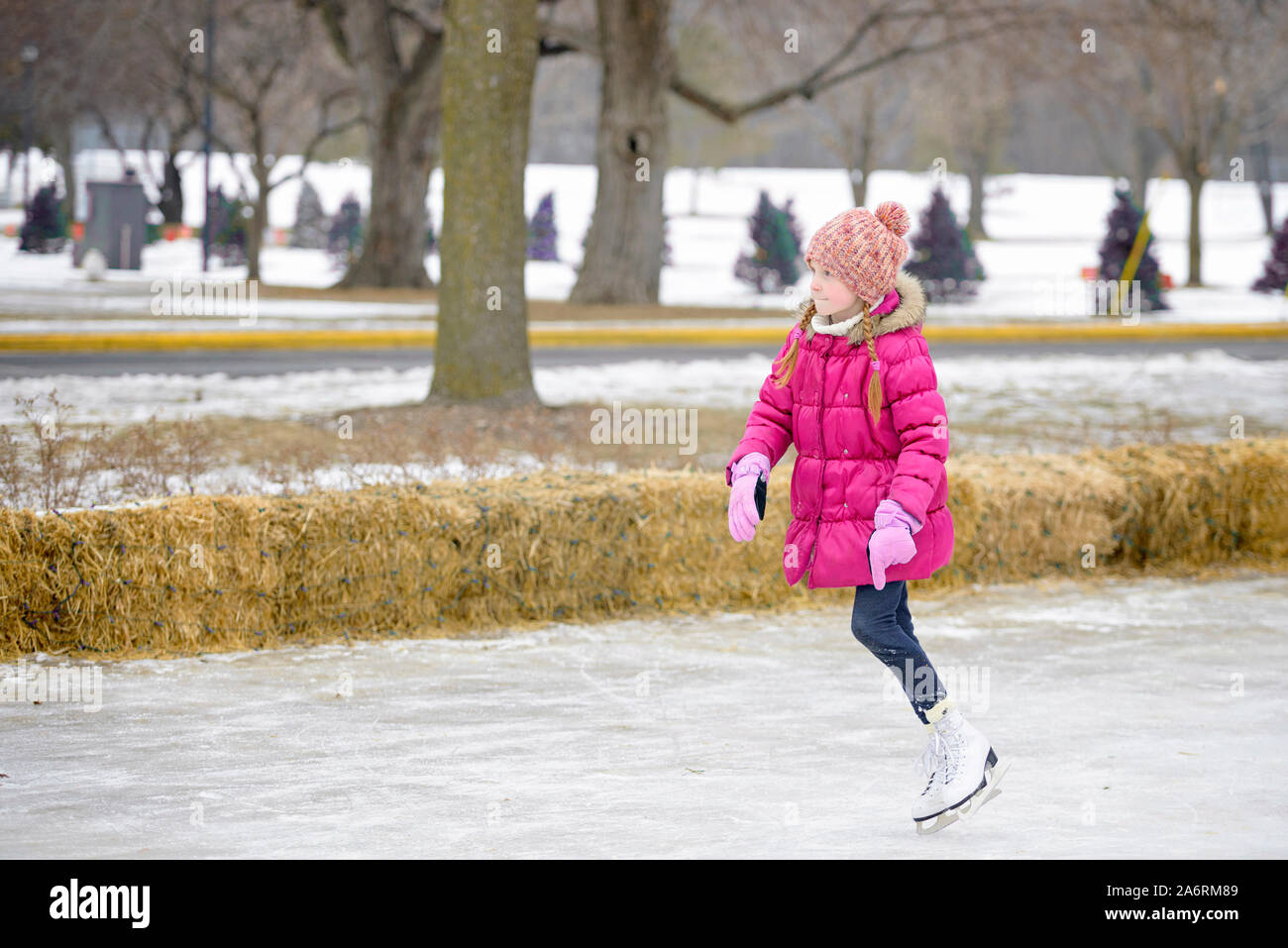 Petite fille aux cheveux rouges le patin à glace en plein air Banque D'Images