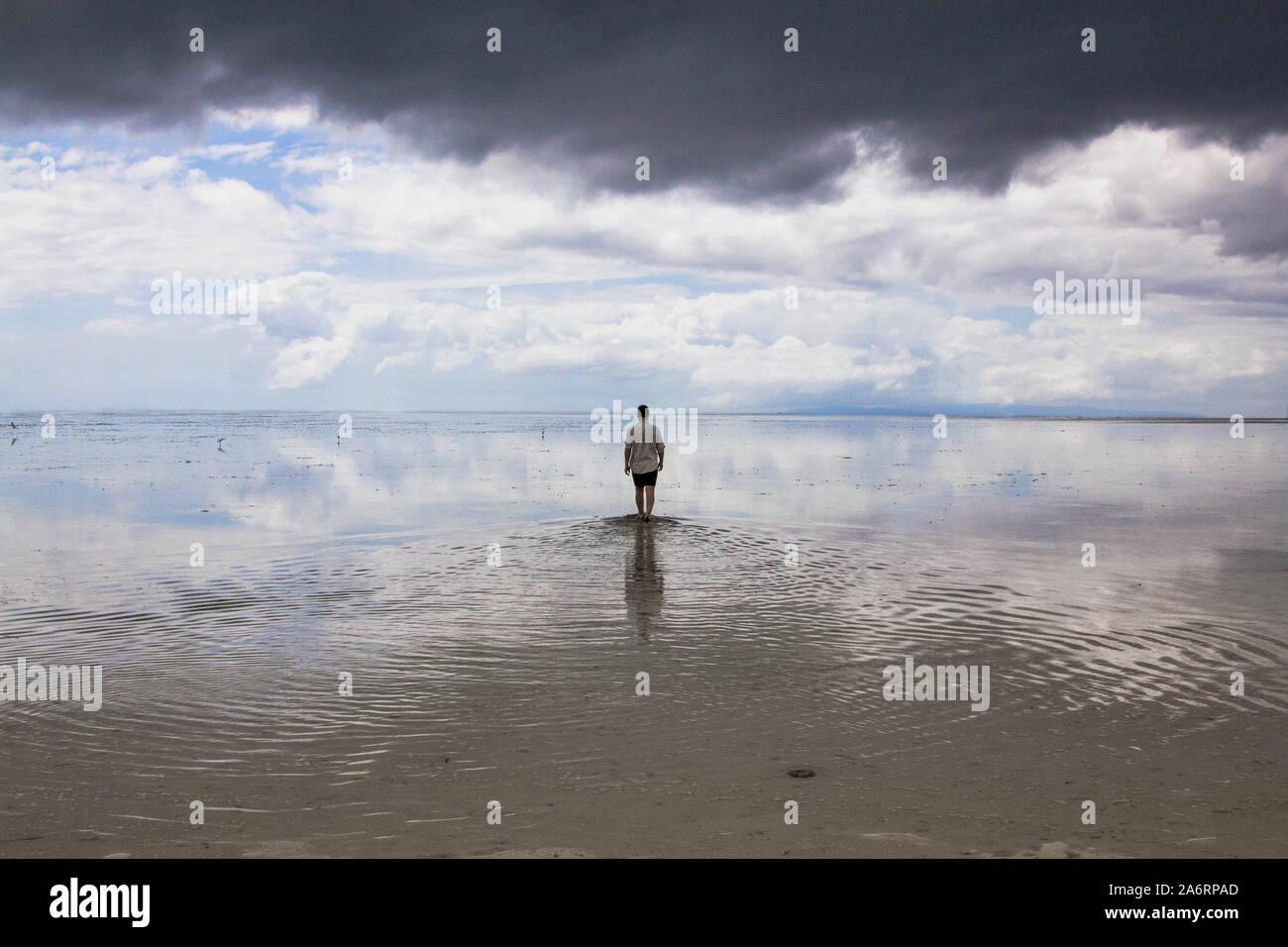 Homme marchant sur l'eau cristalline de l'île vierge en miroir aux Philippines Banque D'Images