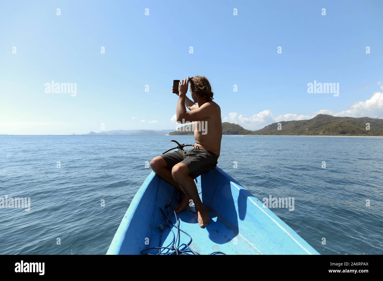 Vue arrière de man with mobile phone sur l'arc d'un bateau Banque D'Images