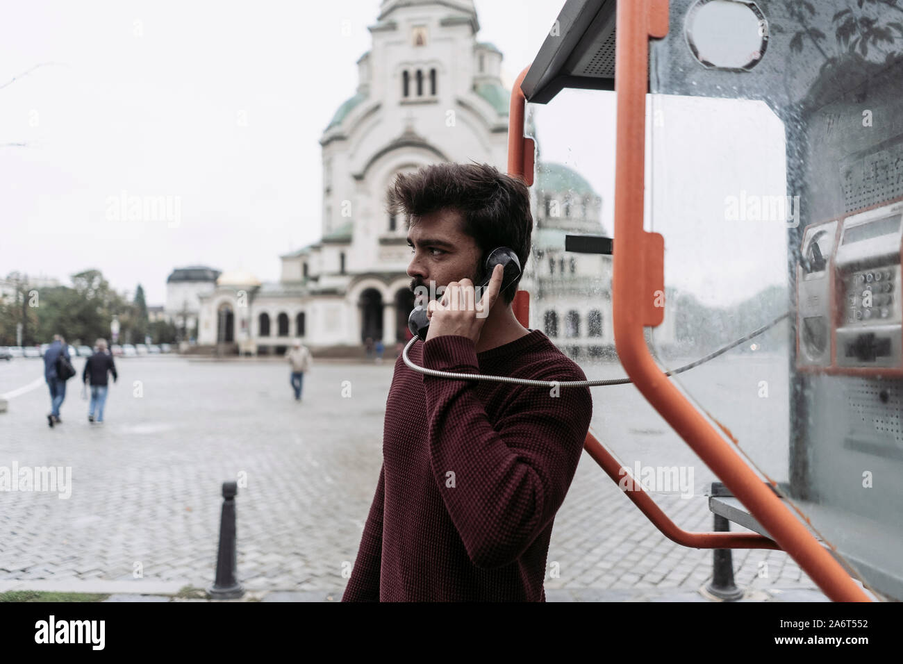 Un jeune homme un appel dans une cabine téléphonique Banque D'Images