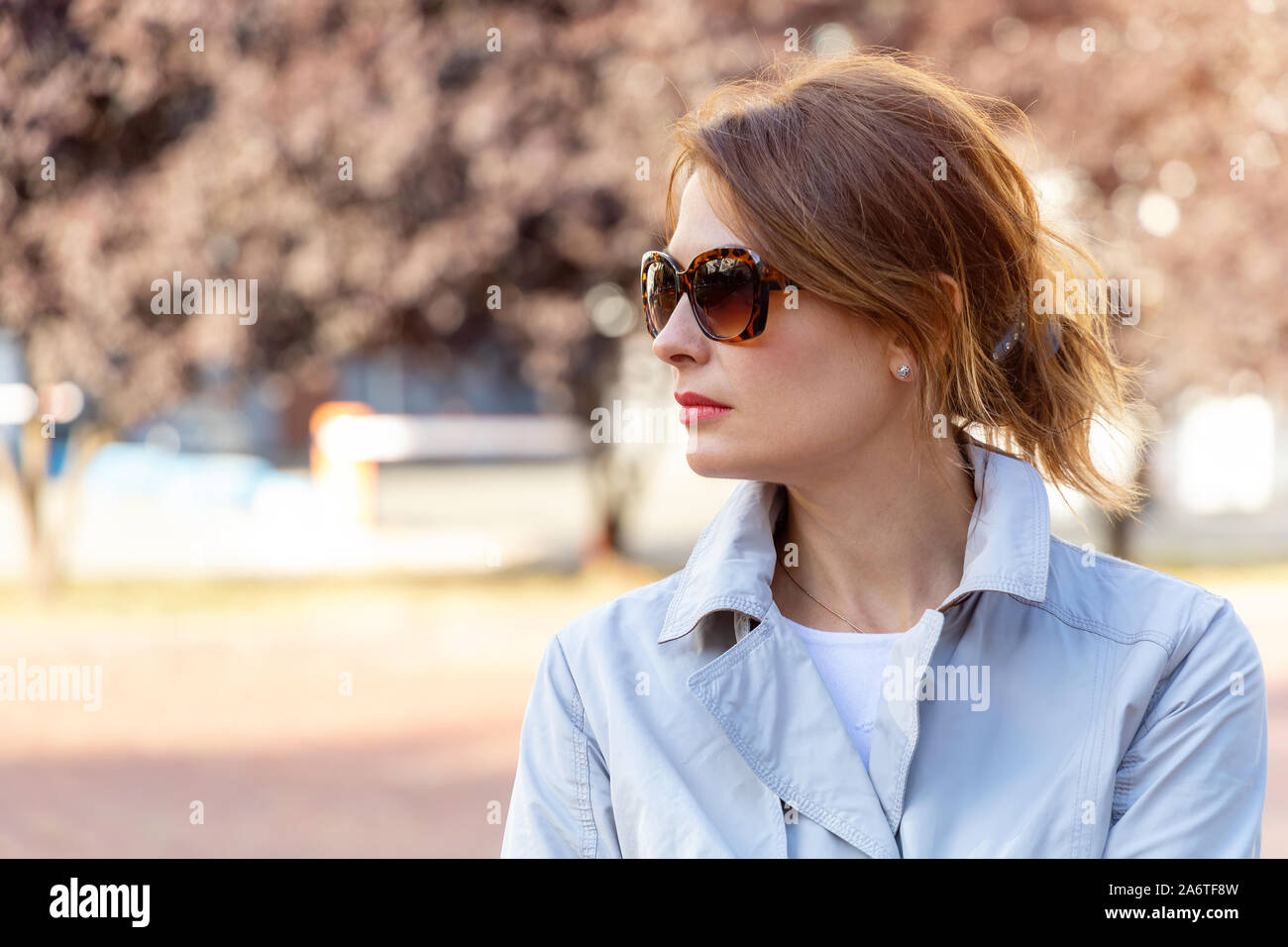 Belle femme d'âge moyen dans les lunettes de soleil sur fond de parc de la ville. Banque D'Images