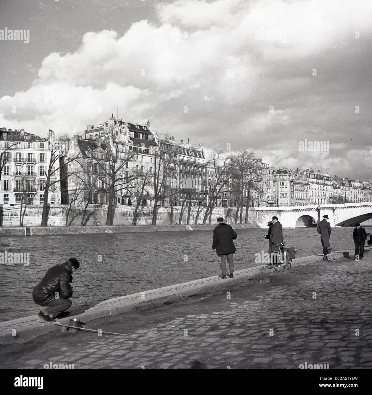 Années 1950, historique, hommes parisiens debout pêchant sur la senne au quai de la Tourville, Paris, France. Banque D'Images