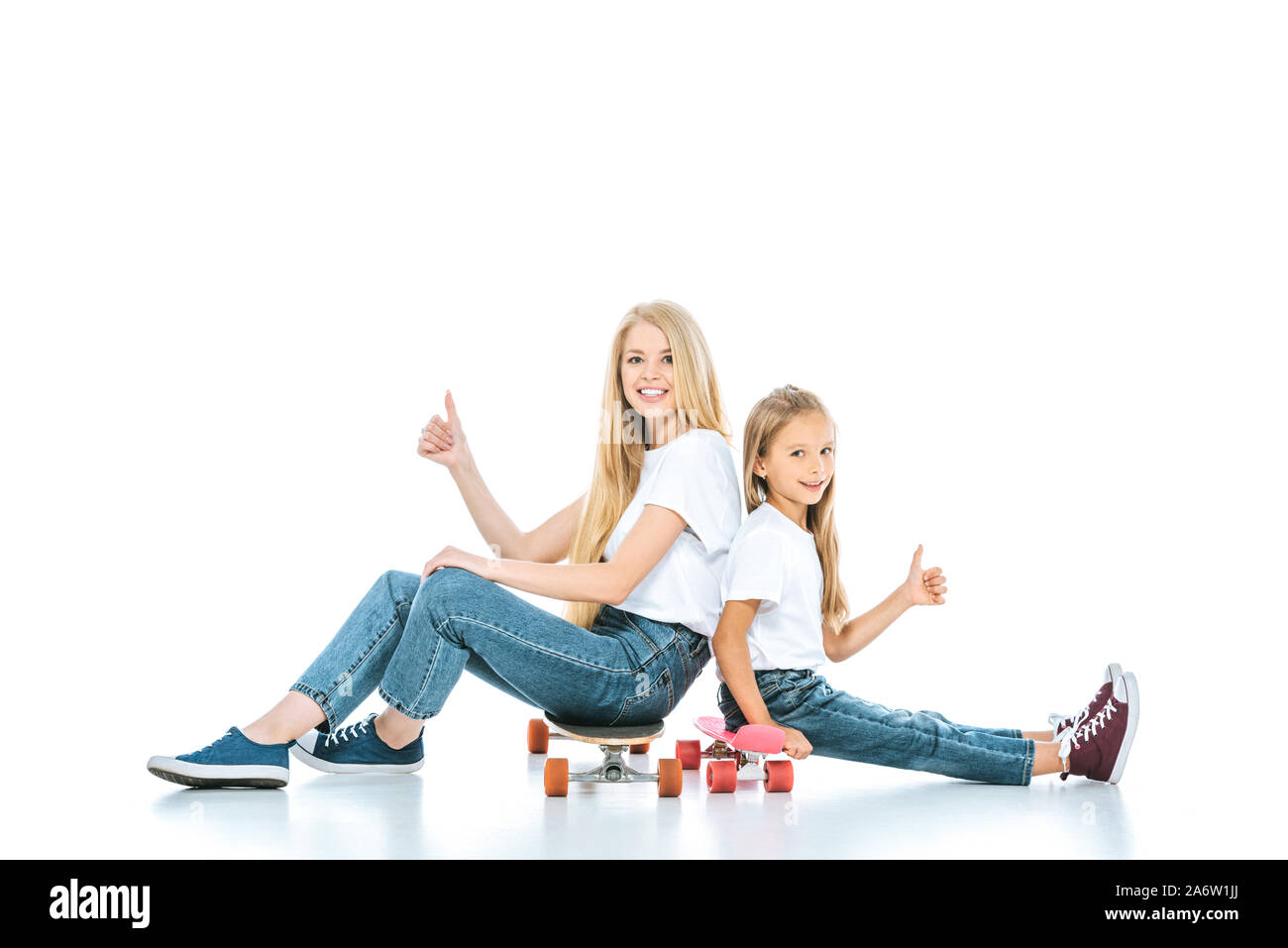 Happy mother and daughter sitting sur penny conseils et showing Thumbs up on white Banque D'Images