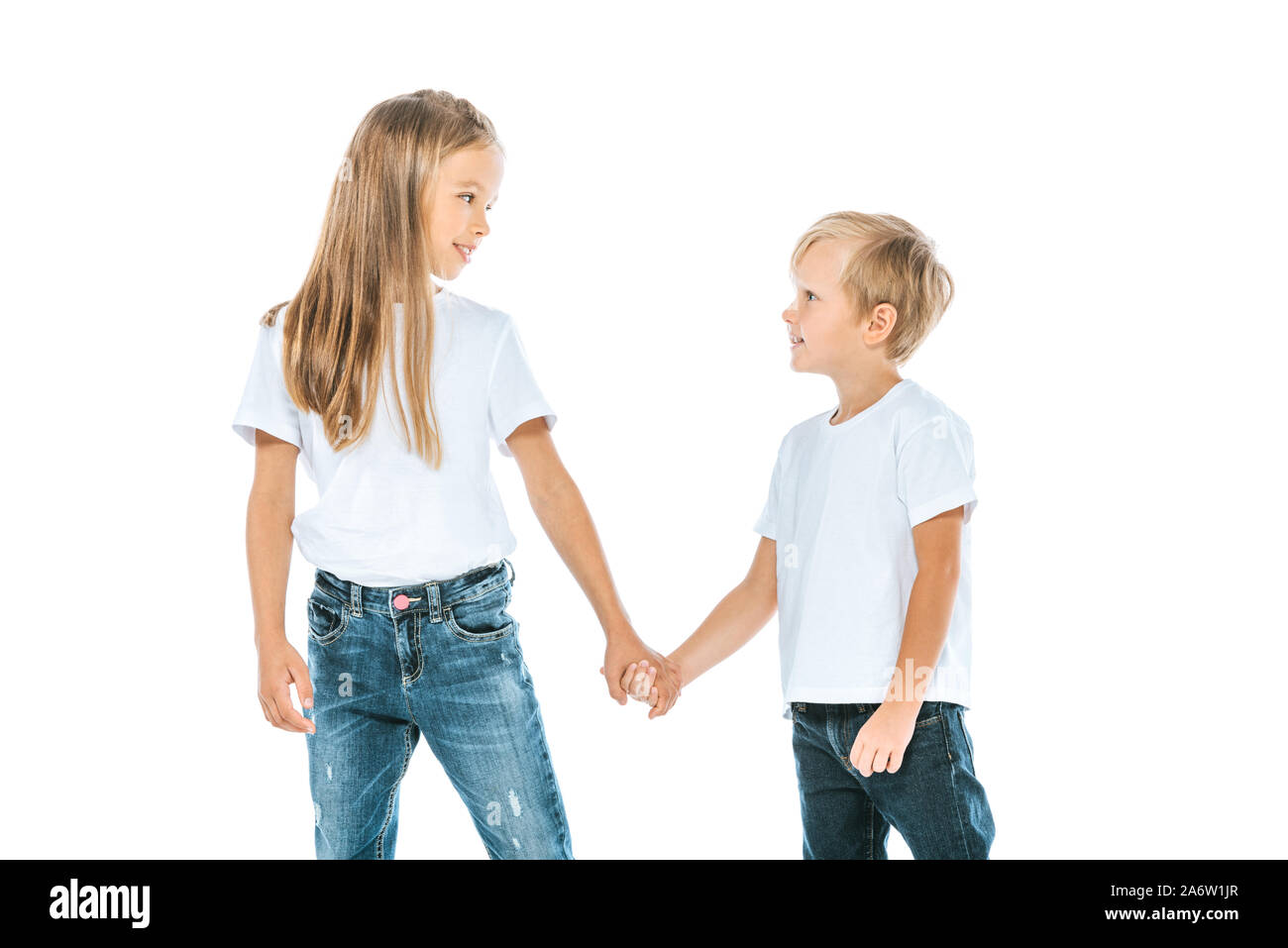 Heureux soeur et frère en denim jeans holding hands isolated on white Banque D'Images