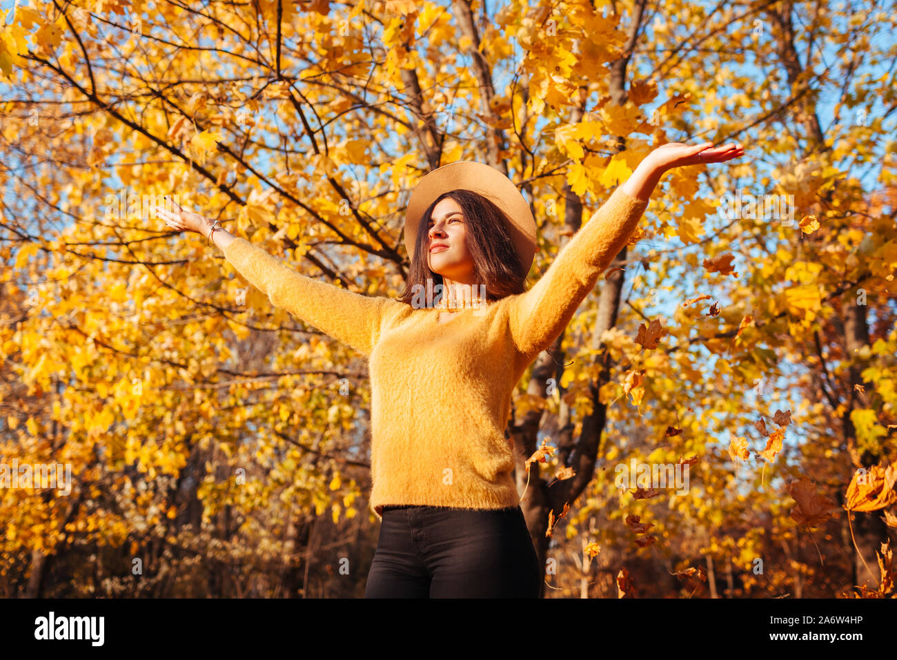Activités de saison d'automne. Woman throwing leaves in autumn forest au coucher du soleil. Jeune femme ayant l'amusement à l'extérieur profiter de la nature Banque D'Images