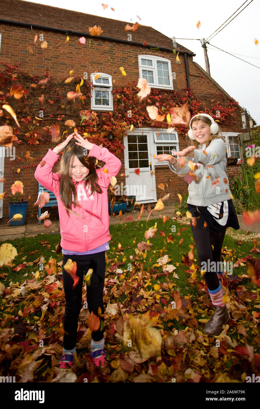 Les jeunes filles jouant avec des feuilles dans le jardin arrière, Angleterre Banque D'Images