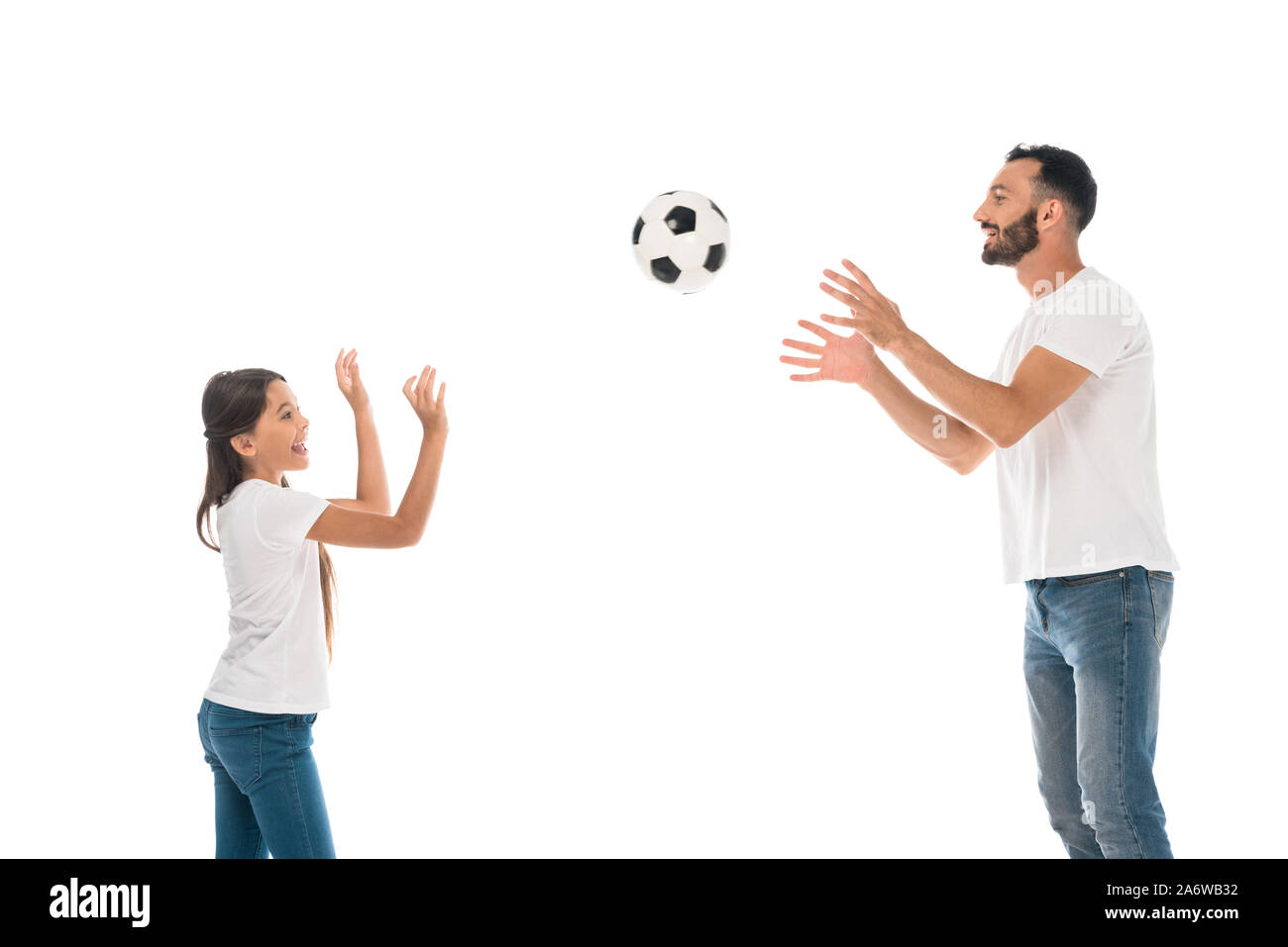 Vue latérale d'heureux père de jeter dans l'air football près de fille isolée sur fond blanc Banque D'Images