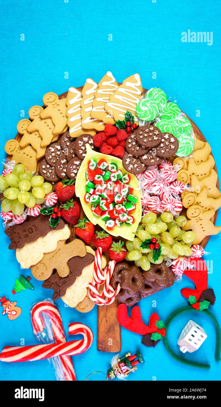 Bonnes fêtes de Noël coloré lumineux dessert grand plateau de pâturage avec planche de charcuterie d'épice, biscuits, bonbons et fruits sur colo pop lumineux Banque D'Images