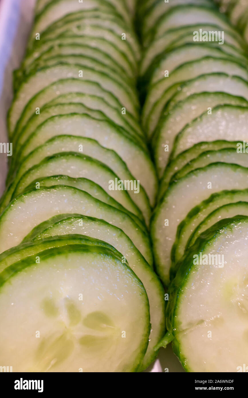 Deux rangées de tranches de concombre avec leurs pelures sont vus de près dans leur portion blanche bac. Banque D'Images