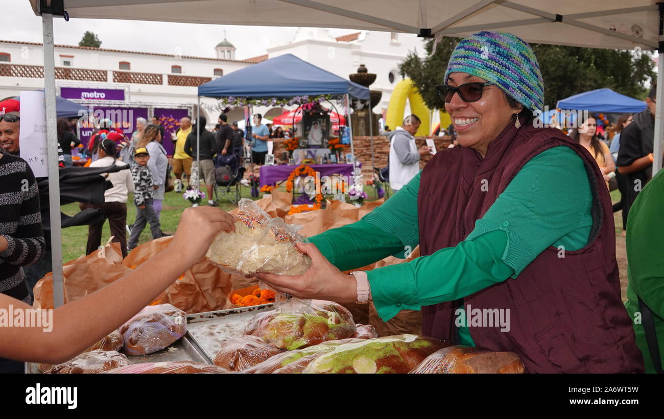 A smiling woman in a market stall propose des saveurs de pan de muerto lors d'une manifestation le Jour des Morts. Banque D'Images