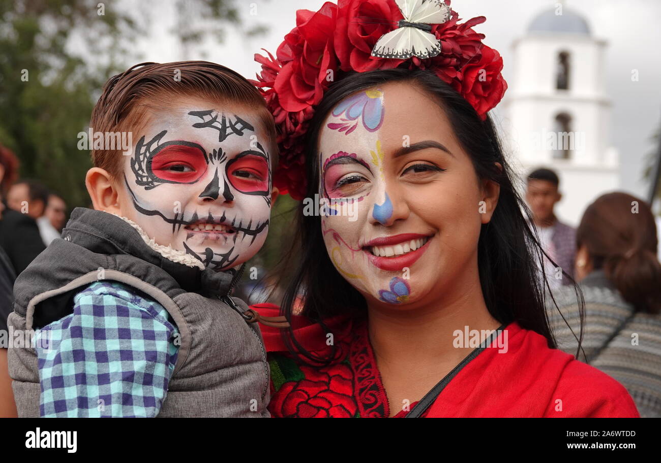 Jeune mère hispanique et petit garçon portant crâne en sucre maquillage, assistant à Dia de los Muertos événement à Mission San Luis Rey. Banque D'Images