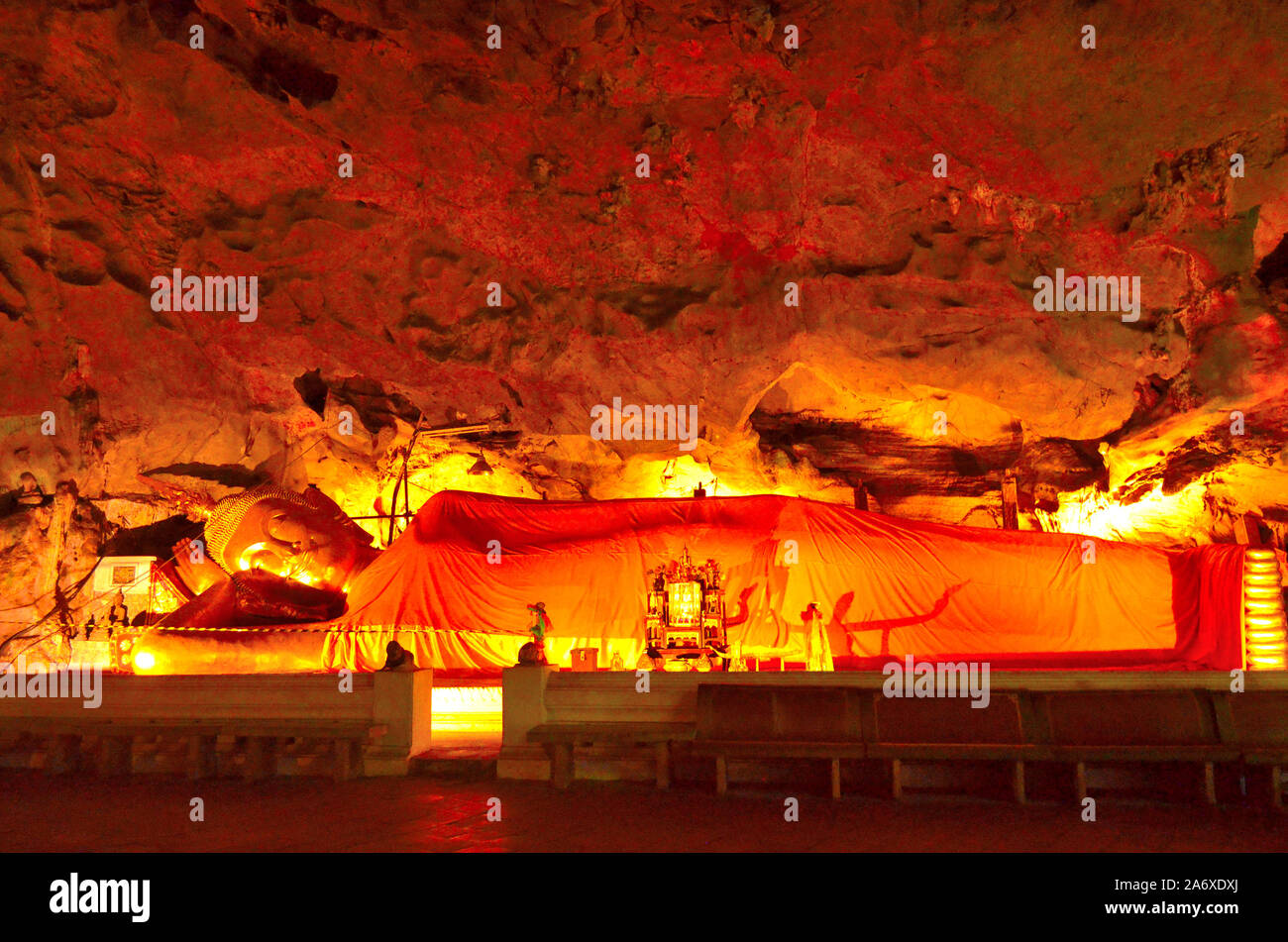 Un Bouddha couché libre baigné dans une lueur orange en face d'un rock face à Khao Luang Cave Petchaburi Thaïlande Banque D'Images