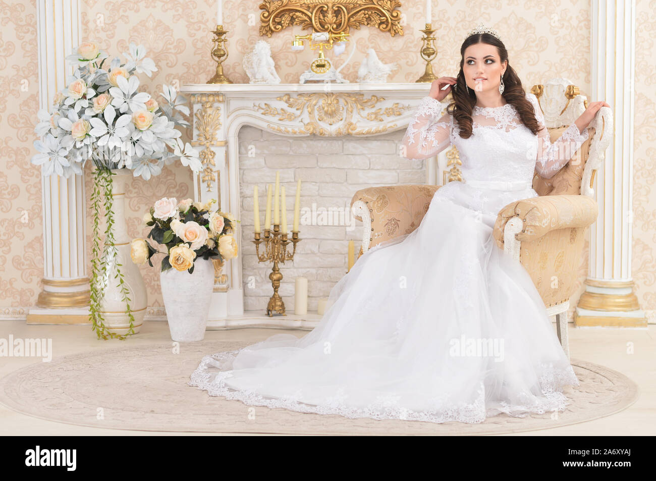 Portrait of young woman in white dress posing in modern interior Banque D'Images