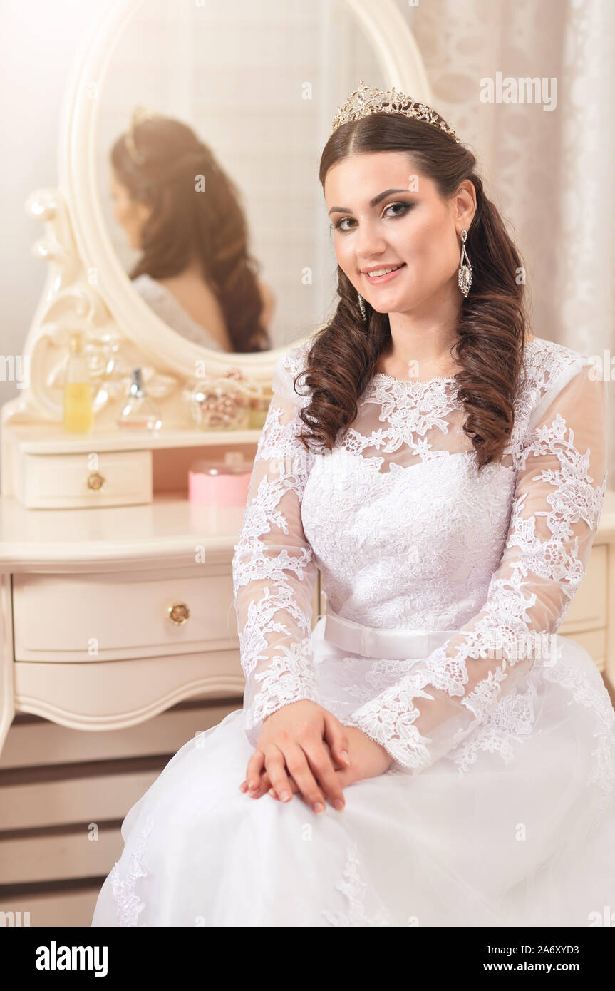 Belle jeune mariée en robe blanche posant près de le miroir Banque D'Images