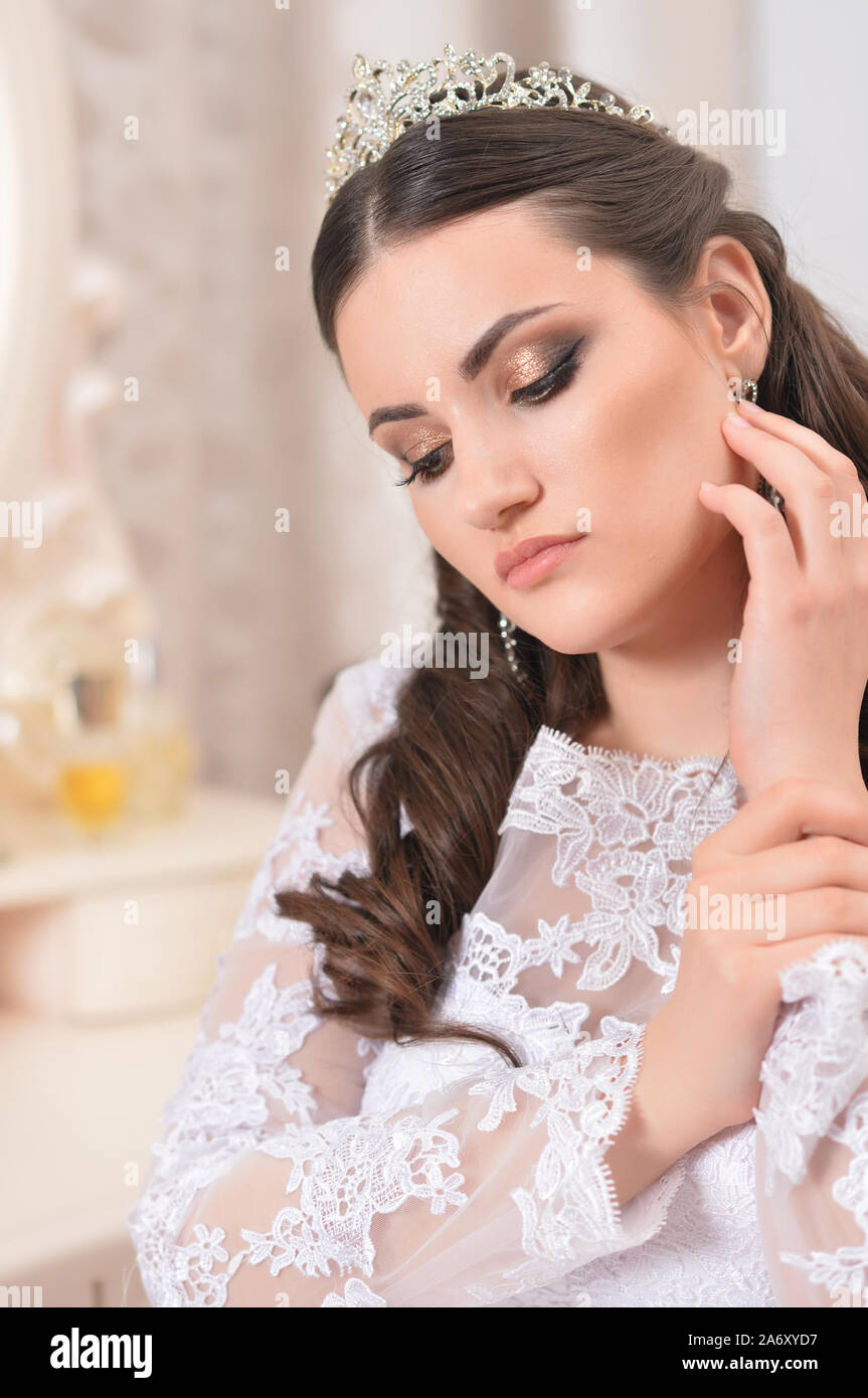 Belle jeune mariée en robe blanche posing at home Banque D'Images