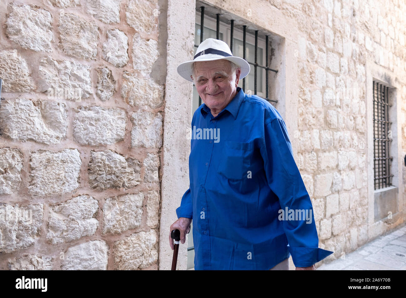Un homme plus âgé sur son chemin à la maison de shopping s'arrête pour poser pour une photo. Dans la vieille ville de Dubrovnik en Croatie. Banque D'Images