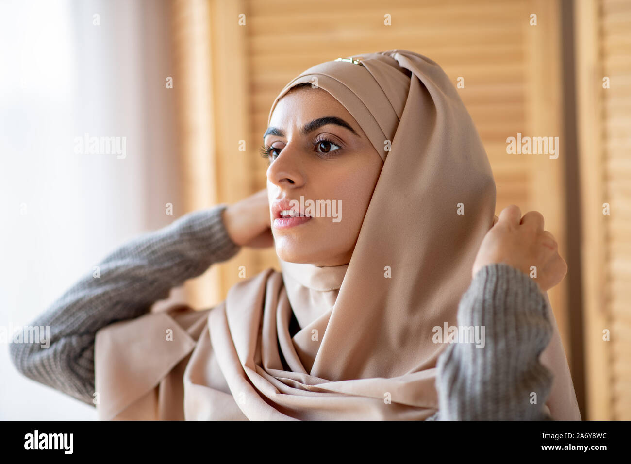 Jolie jeune fille musulmane s'habille en hijab dans la chambre Banque D'Images