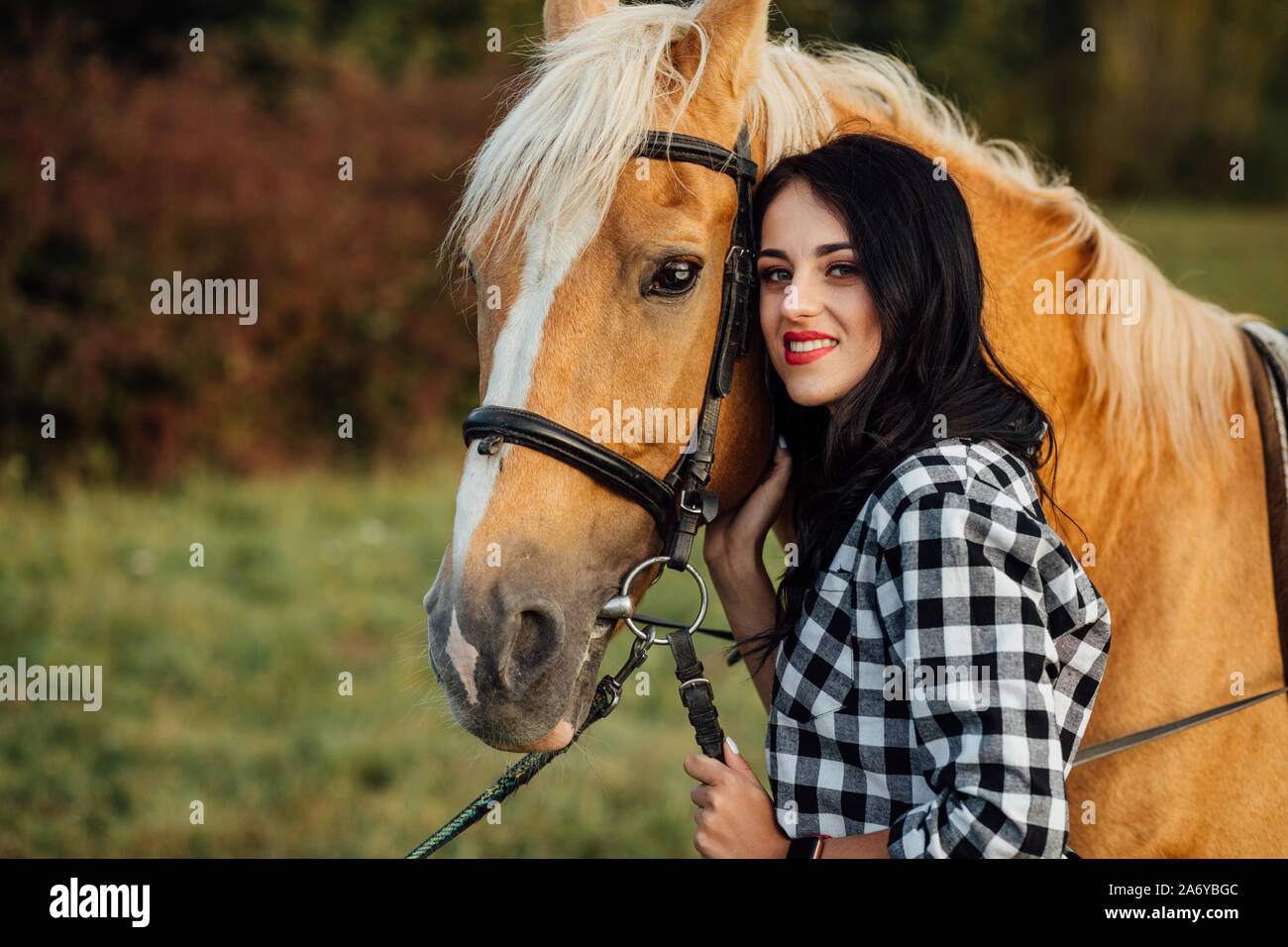 Belle jeune fille avec son cheval au coucher du soleil Banque D'Images