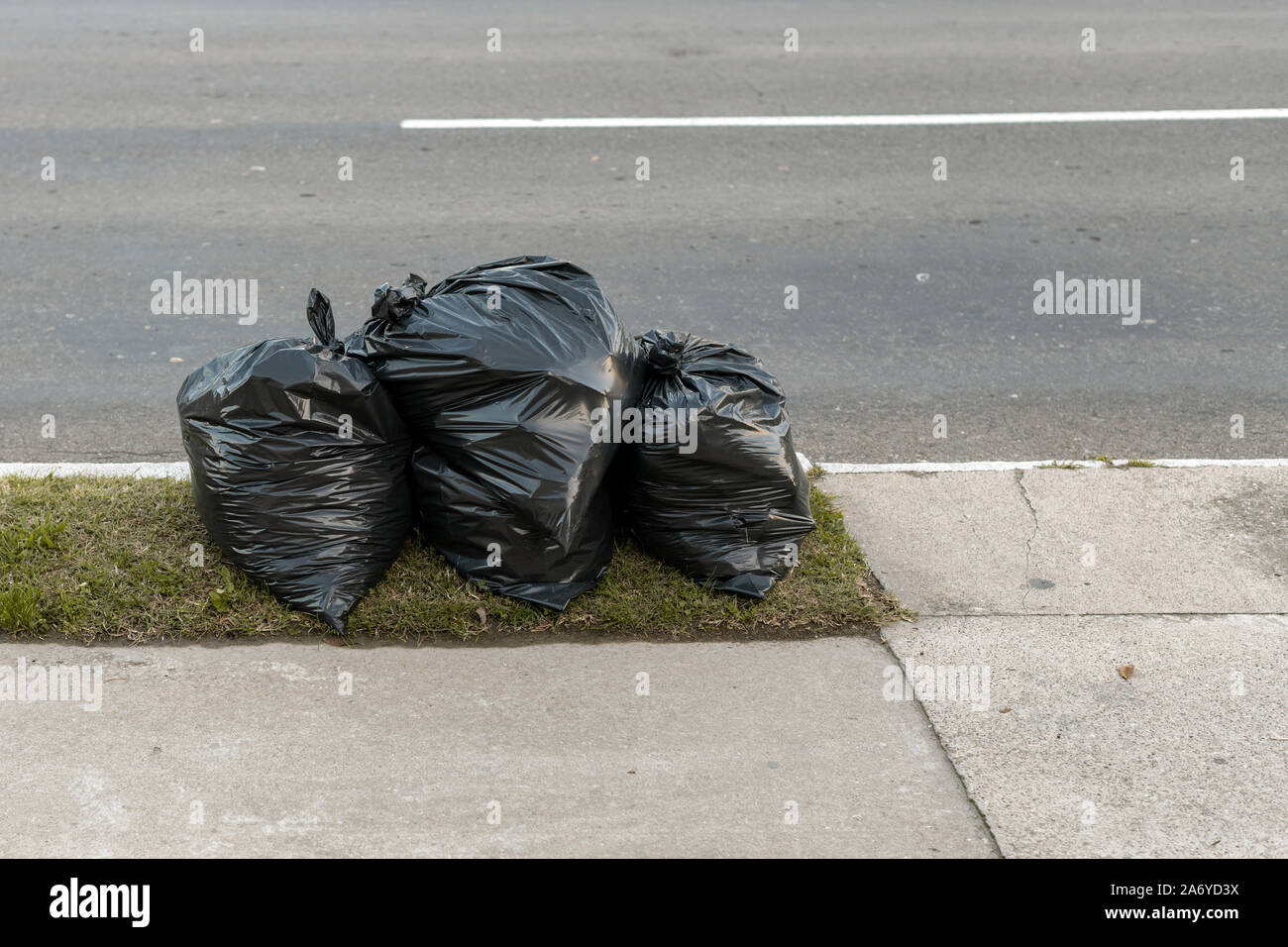 Sacs poubelles en plastique sur la rue par la route Banque D'Images