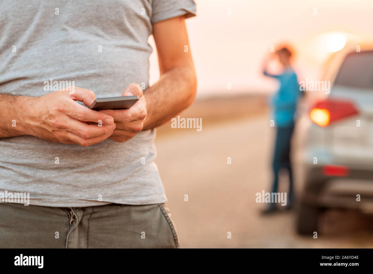 Man texting assistance routière pour véhicule est tombé en panne après le coucher du soleil en automne, selective focus Banque D'Images