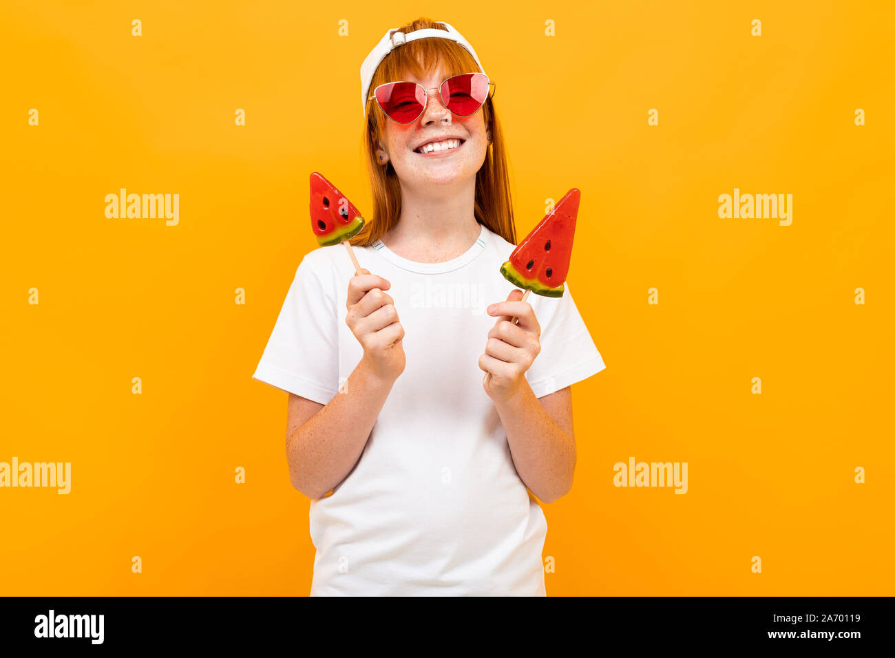 Belle jeune fille rousse dans un T-shirt blanc sur un arrière-plan d'un mur orange, immersive, portrait psychologique Banque D'Images