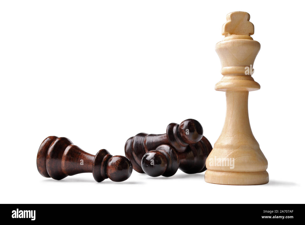 En bois de couleur claire King chess piece debout entouré par l'opposition des pions couchés sur le côté dans un jeu de stratégie, on white Banque D'Images