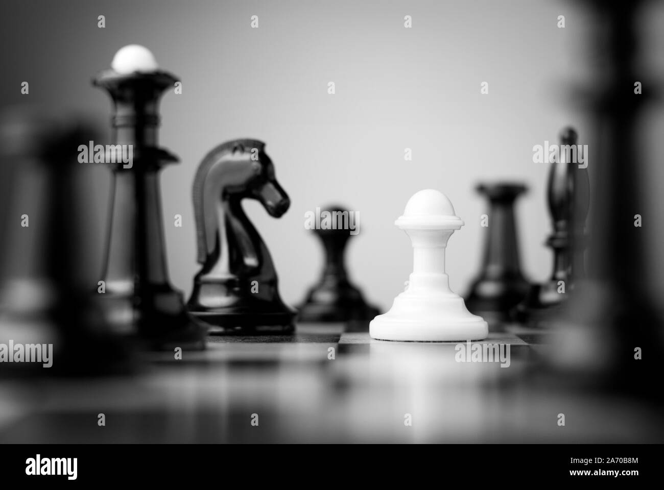 Le pion blanc entouré par des pièces d'échecs sur un échiquier Banque D'Images