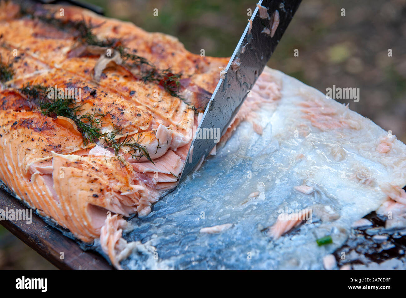 Un cuisinier est de couper un morceau de saumon avec un couteau Banque D'Images