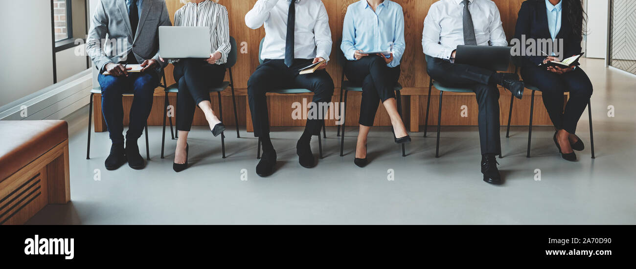 Groupe diversifié de méconnaissable businesspeople sitting in a row dans des chaises dans la zone de réception d'un bureau en attente de leurs nominations d'entrevue Banque D'Images
