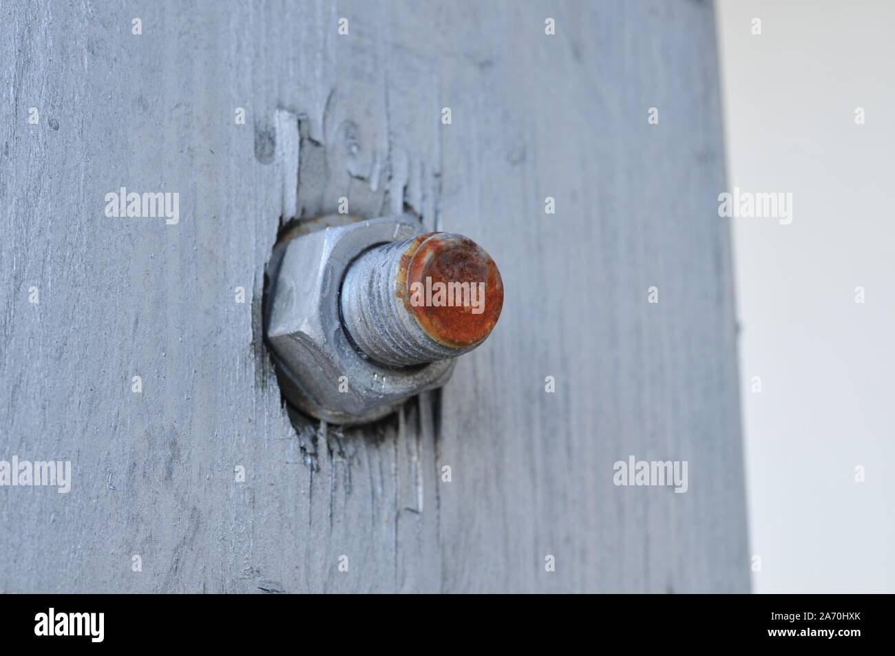 Vis et écrou rouge rouillé sur un mur en bois blanc Banque D'Images