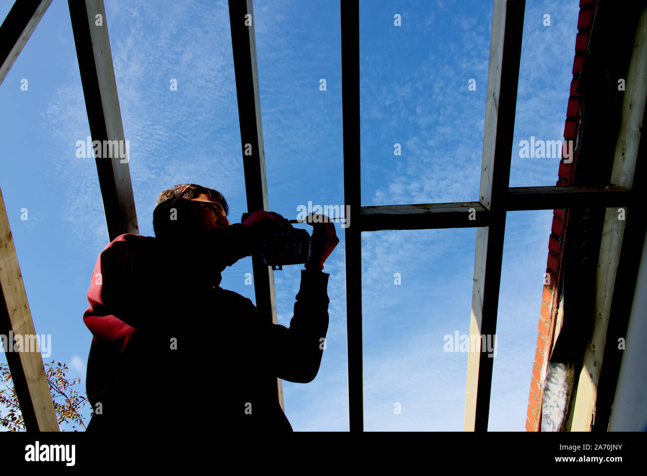 Ouvriers construire un toit sur une véranda extension sur une maison en brique rouge Banque D'Images