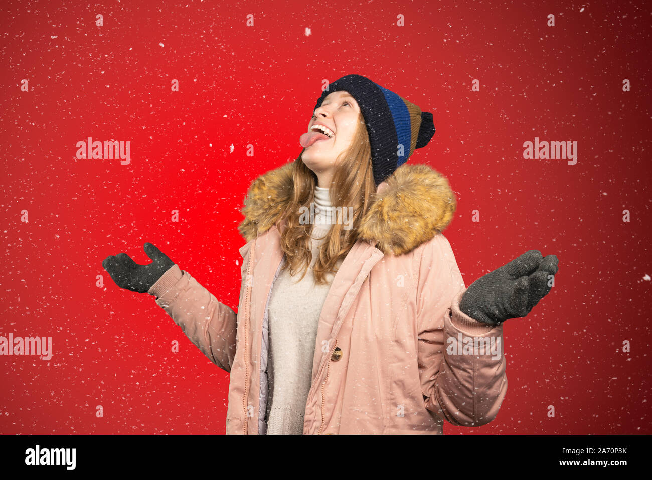 Une jeune femme tente d'attraper des flocons de neige avec sa bouche Banque D'Images