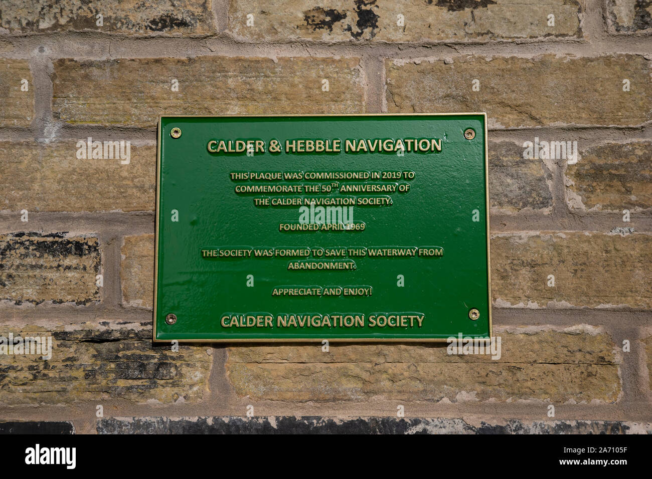 Une plaque métallique verte sur un mur sur le côté de l'affaire Calder & Hebble La navigation à Mirfield, commémorant le 50e anniversaire de la société. Banque D'Images