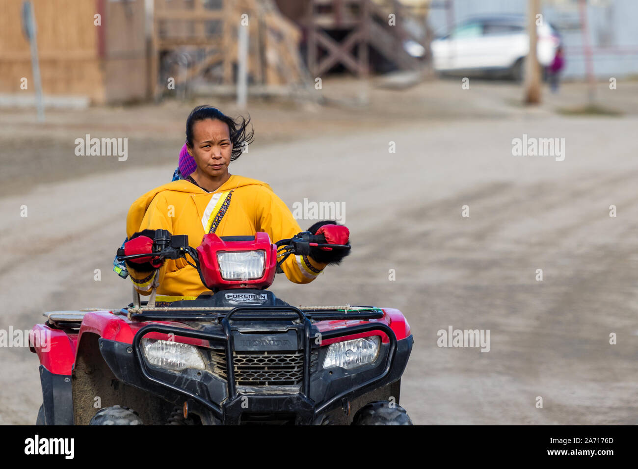 Une femme inuit locaux la conduite d'un quadricycle à Clyde River, Canada. Banque D'Images