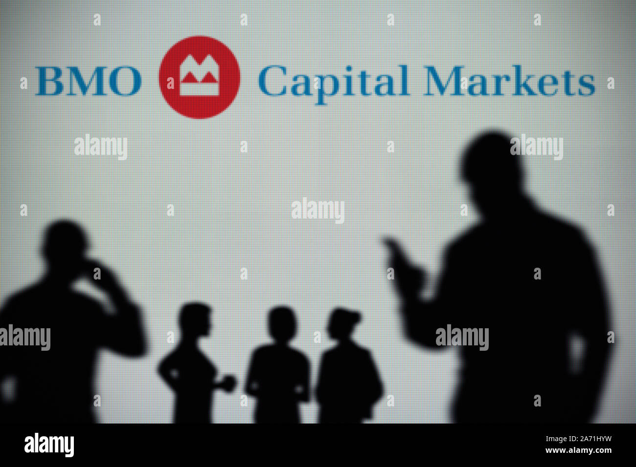BMO Marchés des capitaux Le logo est visible sur un écran LED à l'arrière-plan tandis qu'une silhouette personne utilise un smartphone (usage éditorial uniquement) Banque D'Images