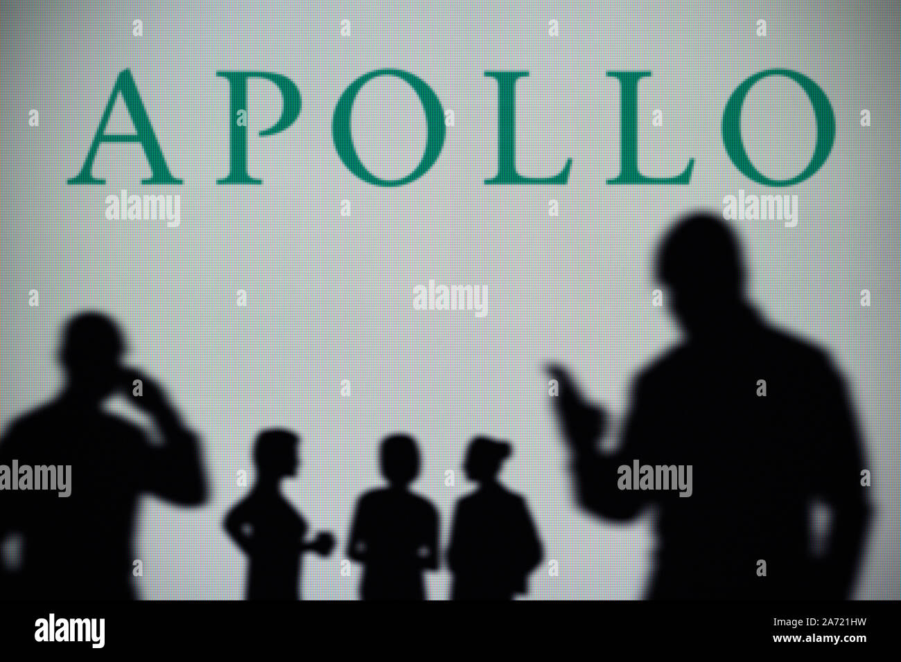 L'Apollo Global Management logo est visible sur un écran LED à l'arrière-plan tandis qu'une silhouette personne utilise un smartphone (usage éditorial uniquement) Banque D'Images