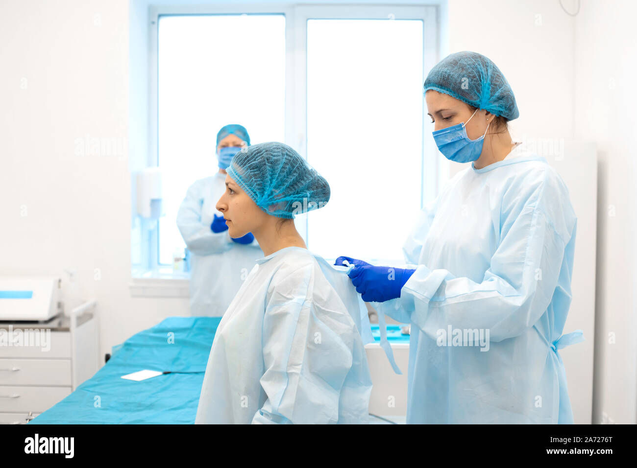 Une infirmière robes une chirurgien dans un costume stérile avant la chirurgie. Banque D'Images