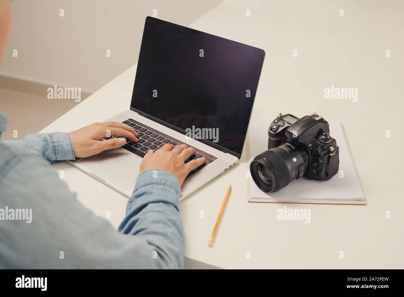 Jeune homme photographe travaillant sur un ordinateur. Bureau avec clavier, appareil photo, ordinateur portable et de l'objectif. Banque D'Images